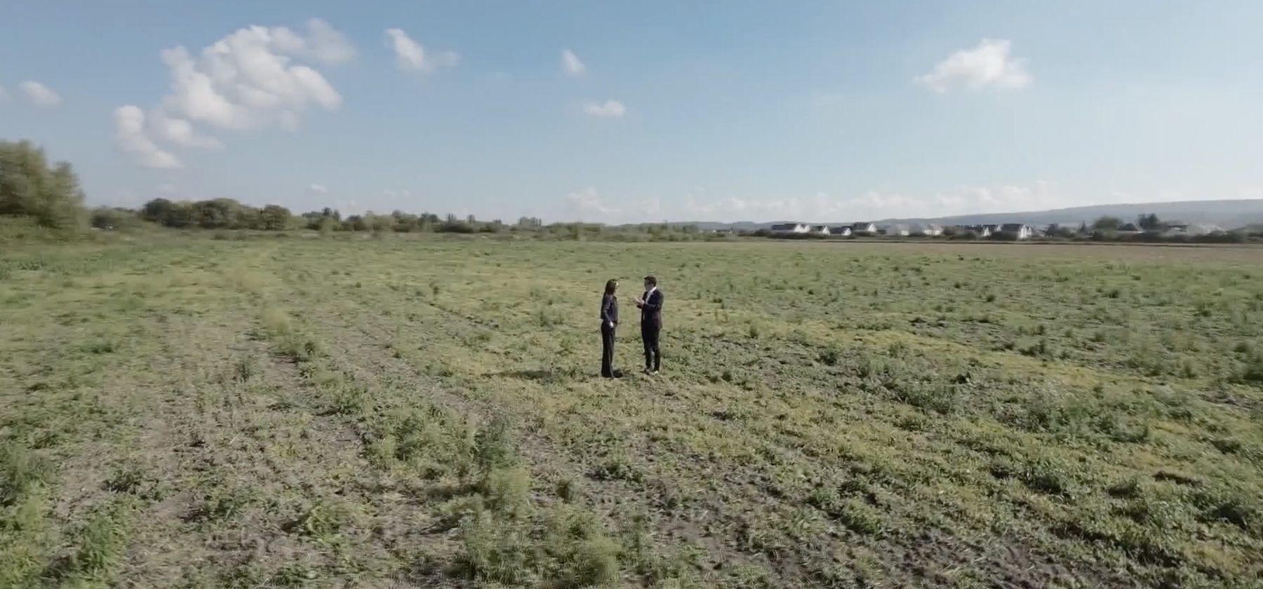Aerial shot of two people talking in an open field